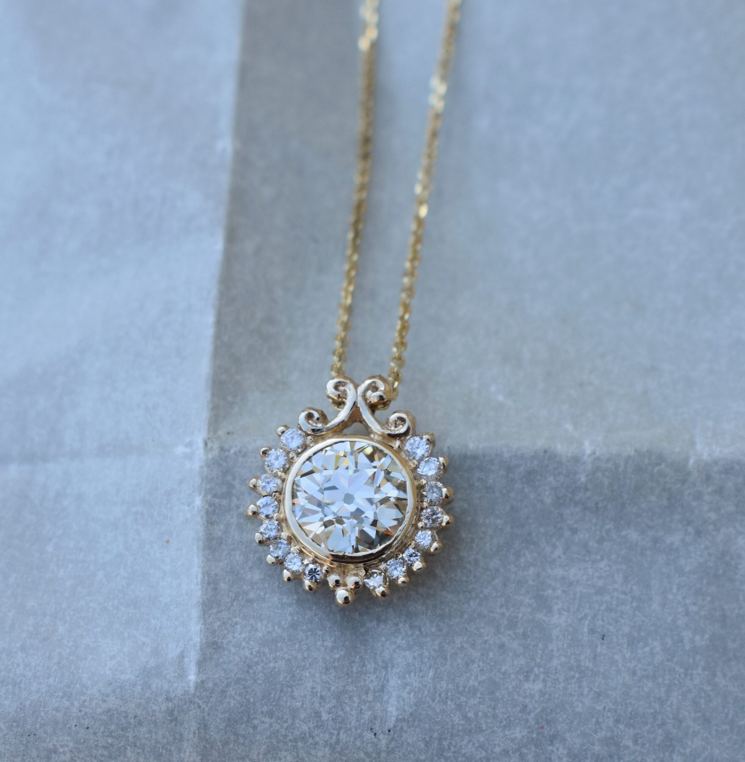 A signature Anderson halo diamond pendant, bench-set in 14k gold